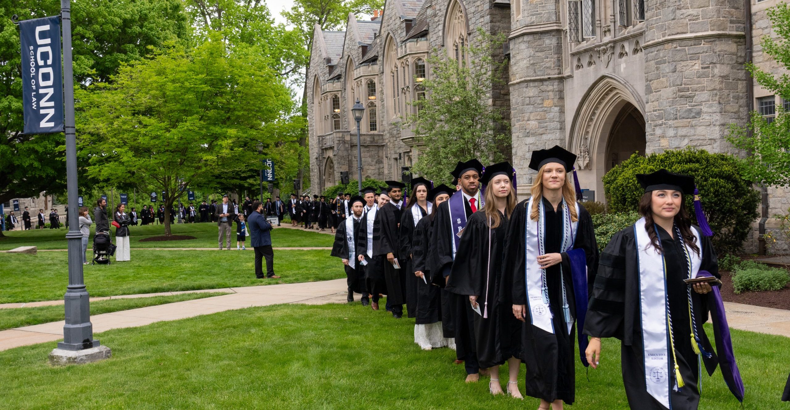 Students in graduation attire walking in front of Starr Hall