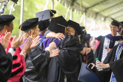 Graduate hugs professor while exiting tent