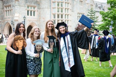 Graduate poses with friends holding cut outs of her face