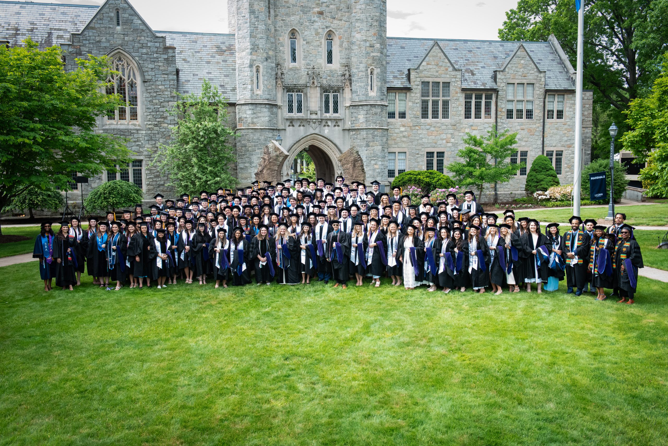 Class photo on lawn in front of U shaped statue and stone building